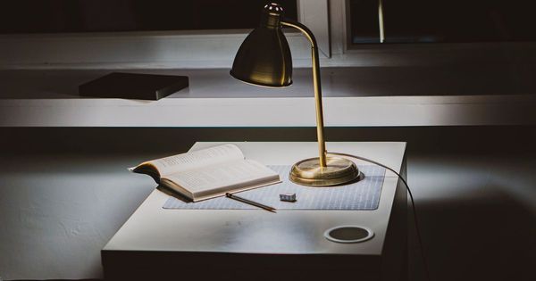 Libro abierto sobre un escritorio con una lámpara encendida